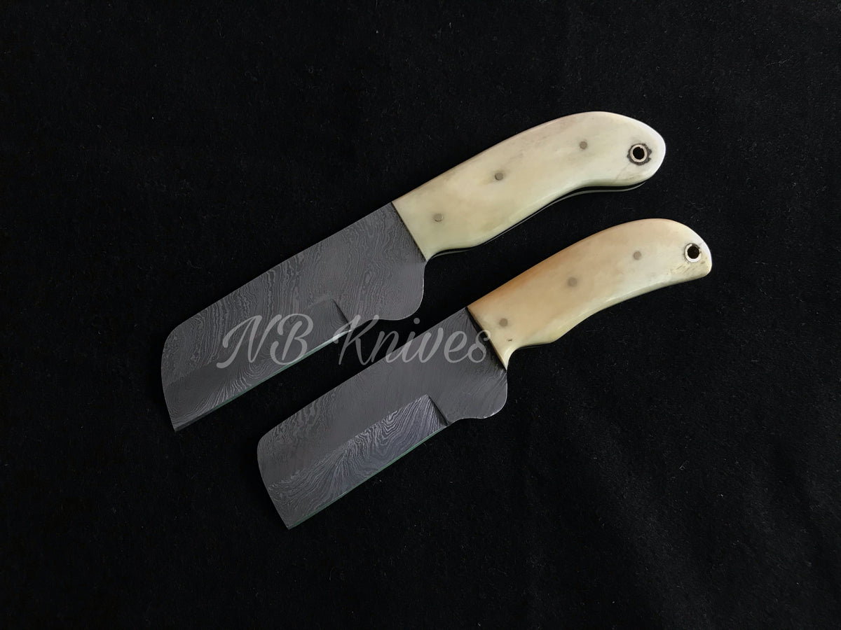 Two custom handmade knives with camel bone handles and black leather sheaths, displayed against a dark background.