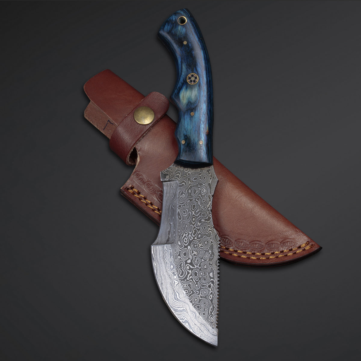 A custom handmade Damascus steel tracker knife with a blue Pakka Wood handle and a leather sheath.