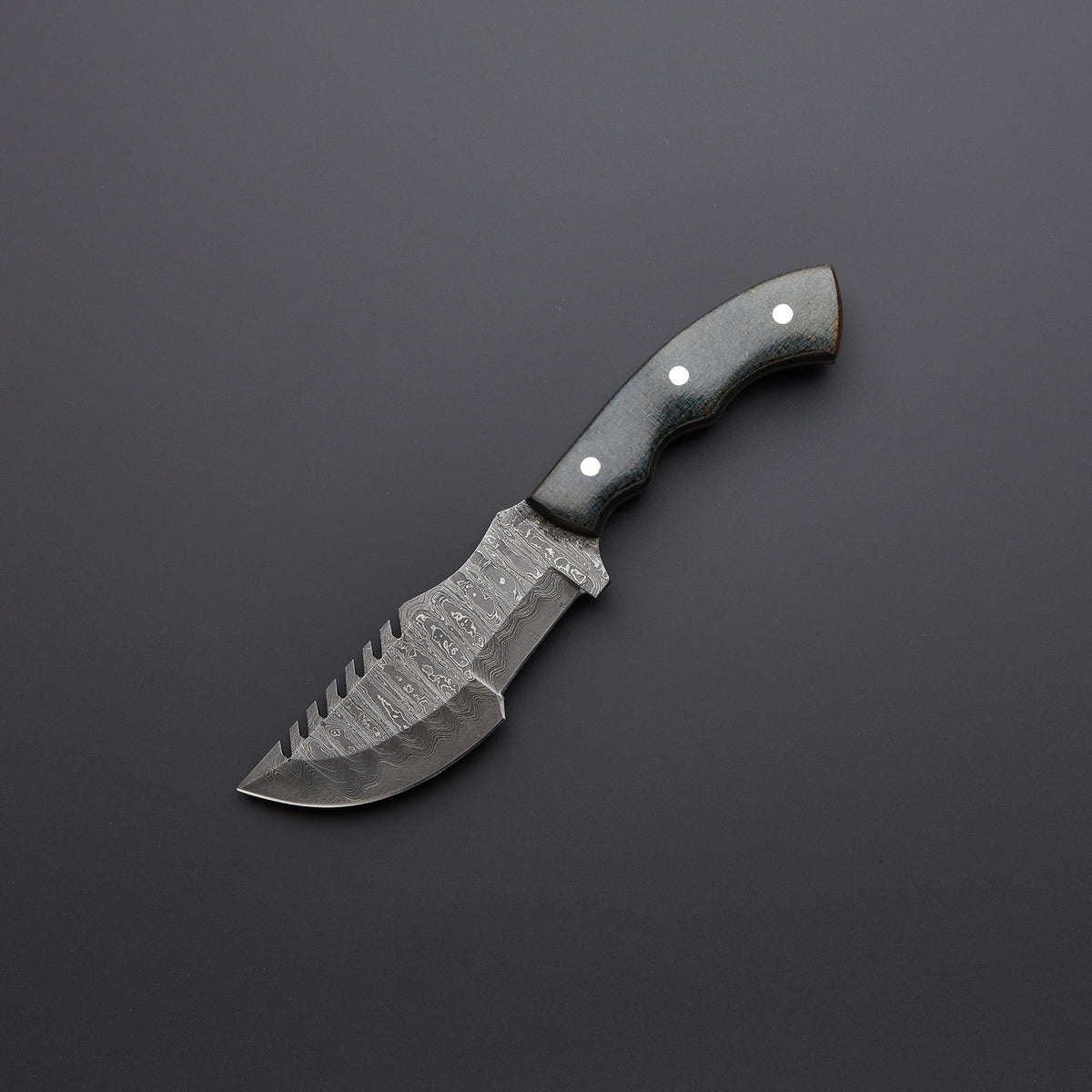 A custom handmade Damascus steel tracker knife with a black micarta handle and a leather sheath.