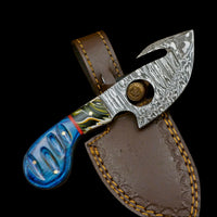 Decorative knife with a blue handle and silver blade in a brown leather sheath on a wooden surface