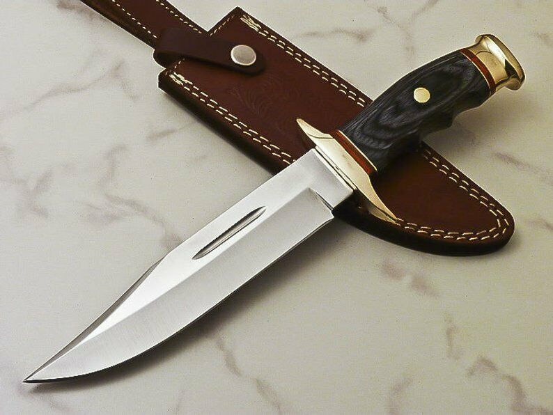 A handmade hunting knife with a stainless steel blade and a wooden and brass handle, displayed next to its brown leather sheath.